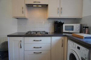 y cocina con fogones y microondas. en Our 2 bedroom house or borders of Bromley and Lewisham is available now! en Catford