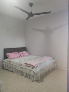 een bed met roze kussens en een plafondventilator bij Homestay MdmMai Private Pool in Masjid Tanah