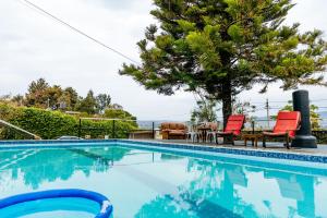 a swimming pool with two red chairs and a tree at Stunning 3-Bed House in Kigali in Kigali