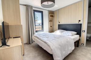 a bedroom with a bed and a tv and a window at Le Chalet d'Angel in Jullouville-les-Pins