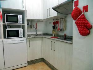 una pequeña cocina con armarios blancos y microondas en Albergue Corredoiras en Padrón