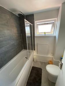 a bathroom with a tub and a toilet and a window at Single and doubles rooms close to central London in London