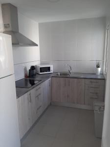 a white kitchen with a sink and a microwave at Apartamento Rota in Rota