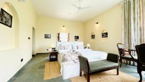 1 Schlafzimmer mit einem weißen Bett und 2 Stühlen in der Unterkunft Kutani Bagh - Best Hotel in Sariska National Park in Tehla
