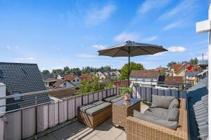 einen Balkon mit Sonnenschirm, Couch und Tisch in der Unterkunft SEEview Maisonette in direkter Seenähe in Friedrichshafen