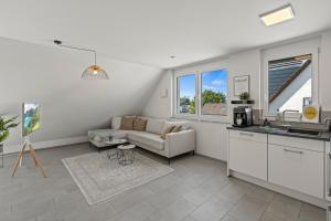 ein weißes Wohnzimmer mit einem Sofa und einer Küche in der Unterkunft SEEview Maisonette in direkter Seenähe in Friedrichshafen + 22 Fotos