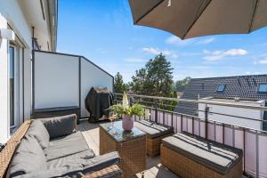 einen Balkon mit einem Sofa, Stühlen und einem Sonnenschirm in der Unterkunft SEEview Maisonette in direkter Seenähe in Friedrichshafen