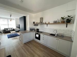 a kitchen with white cabinets and a living room at Cleethorpes - New 2 Bedroom house close to beach in Cleethorpes