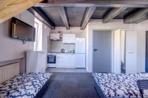 Cet appartement comprend une chambre avec un lit et une cuisine avec des placards blancs. dans l'établissement Noclegi pokoje gościnne Żeglarz, à Gdynia