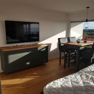 ein Wohnzimmer mit einem großen TV und einem Esstisch in der Unterkunft LITTLE SKYSUITE Terrassenhaus W 94 in Cuxhaven