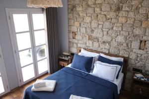 ein Schlafzimmer mit einem blauen Bett und einer Backsteinwand in der Unterkunft Adacan Hotel Alaçatı in Alacati
