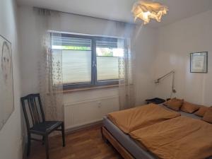 1 dormitorio con 1 cama, 1 silla y 1 ventana en Wohnung mit Terrasse und eigenem Parkplatz, en Nabburg