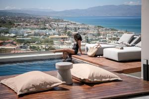 a woman sitting on the edge of a swimming pool at Alectrona Living Crete, Villa Ãcro in Plataniás