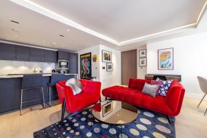a living room with red furniture and a kitchen at Stylish 2-BR ground floor apt in Chelsea in London
