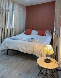 a bed with red pillows and a table with a lamp at Appartement loft terracotta in Manosque