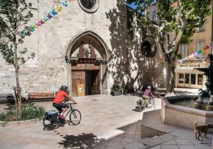 two people riding bikes in front of a building at Appartement loft terracotta in Manosque +8 photos