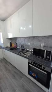 a kitchen with white cabinets and a stove top oven at Cazare cartier Milano in Oradea