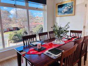 uma sala de jantar com uma mesa de madeira e uma grande janela em Double bedroom in Sharehouse in Canberra and Queanbeyan em Queanbeyan