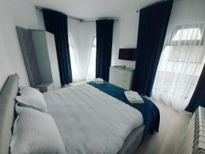 1 dormitorio con 1 cama grande y cortinas azules en Bucovina Inn en Voronet