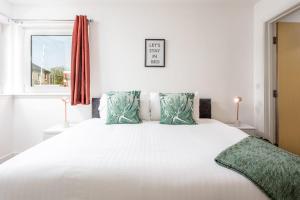 um quarto com uma grande cama branca com almofadas verdes em Walker Suite No52 - Donnini Apartments em Kilmarnock