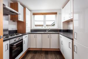 a kitchen with white cabinets and a sink and a window at Elms Way No33 – Donnini Apartments in Ayr
