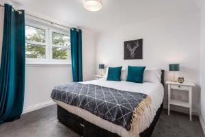 a bedroom with a bed with blue curtains and a window at Elms Way No33 – Donnini Apartments in Ayr