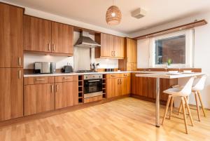 uma cozinha com armários de madeira e uma mesa em Walker Suite No54 - Donnini Apartments em Kilmarnock