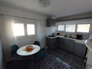 a kitchen with a white table and chairs and a table and a counter at Isthmus Cuddly Nest in Isthmia