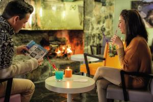 um homem e uma mulher sentados numa mesa em frente a uma fogueira em Belambra Clubs Superbesse - Le Chambourguet em Super Besse