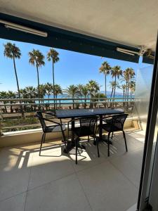 d'une table et de chaises sur un balcon avec vue sur la plage. dans l'établissement Appartement Rottaro luxueux 2 ch 2 sdb face à la mer, à Cannes