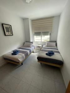 two beds sitting in a room with a window at Casa de Perlas in El Campello