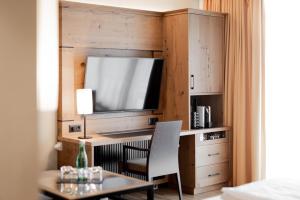 Zimmer mit einem Schreibtisch, einem TV und einem Tisch in der Unterkunft Avita Resort Bad Tatzmannsdorf in Bad Tatzmannsdorf