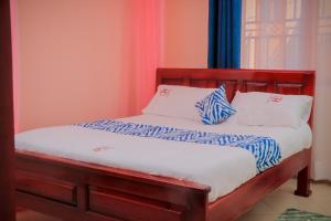 a bed with blue and white pillows on it at Jatheo Hotel Rwentondo in Mbarara