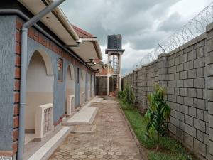 an alley with a brick wall and a clock tower at City Cottages Mbale in Mbale
