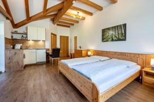a bedroom with a large bed and a kitchen at Urthalerhof Apt Landhaus in Valdaora