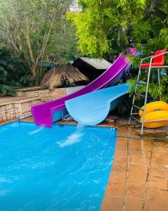 a slide and a chair next to a swimming pool at The Three Trees in Gillitts