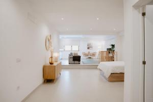 a white bedroom with a bed and a living room at Las Canteras Beach Suites in Las Palmas de Gran Canaria