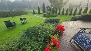 a deck with a bench and flowers and a playground at Burziņi in Kuldīga