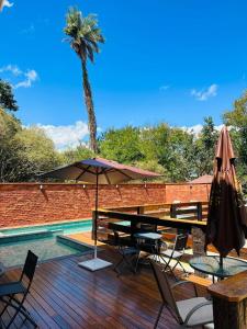 a wooden deck with a table and umbrella next to a pool at Pousada Império in Serra do Cipo
