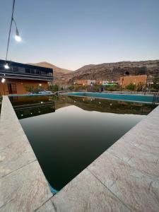 une piscine d'eau en face d'un bâtiment dans l'établissement Sail Alhasa Tourist Resort-Tafila, à Tufailah