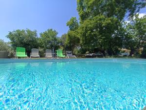 einen großen Pool mit Stühlen und Bäumen in der Unterkunft La ferme d'Andréa au milieu des vignes à 3min à pied du centre piscine chauffée climatisation in Lourmarin