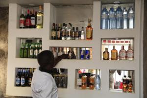 Eine Frau, die hinter einer Bar mit Alkoholflaschen steht. in der Unterkunft Jatheo Hotel Rwentondo in Mbarara