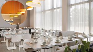 un restaurante con mesas y sillas blancas y ventanas en Hey Lou Hotel Nördlingen en Nördlingen
