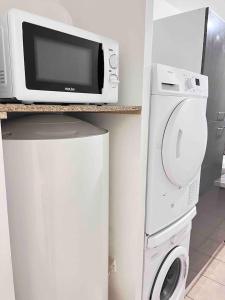 a microwave and a washing machine in a kitchen at 2 pieces - Calme et Lumineux - Parc de La Villette - Stade de France in Aubervilliers