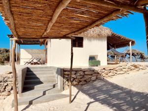 a house on the beach with a thatched roof at LA DUNE DES SONGES in Anakao