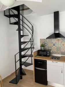 a black spiral staircase in a kitchen next to a counter at CASITA PINYPON in Jerez de la Frontera