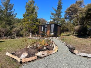 a house constructed out of logs with a garden at Ruru Tiny House in Rangihaeata