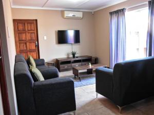 a living room with two couches and a flat screen tv at River Olive Estate Accommodation in Beaufort West