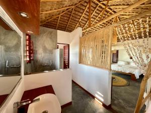 a bathroom with a toilet and a bedroom at LA DUNE DES SONGES in Anakao