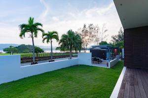 a backyard with a white fence and palm trees at Comfort Villa YAGAJI in Nago